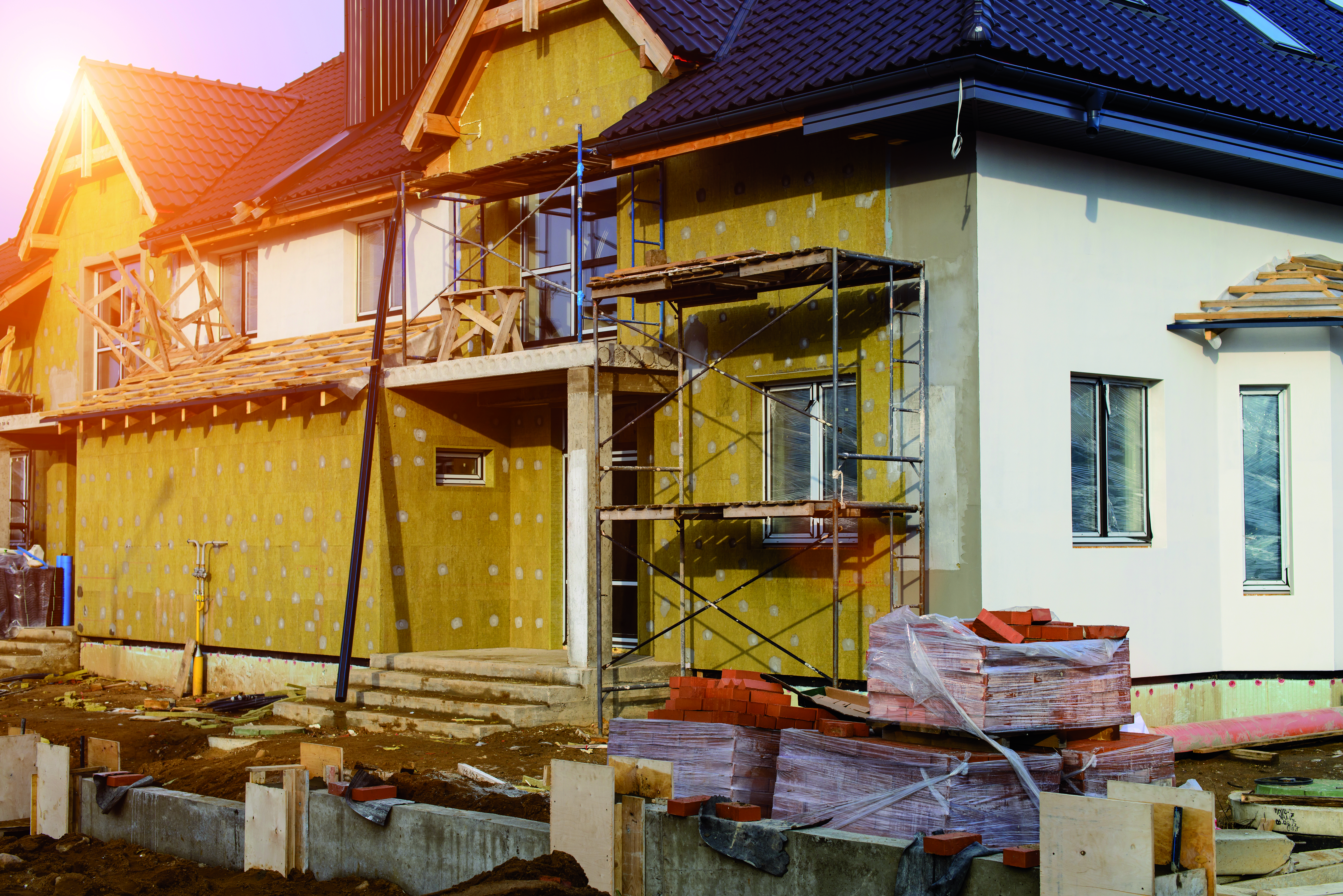 maison en cours de rénovation à Cholet : une partie de la façade avec de la laine de bois et échafaudage devant et l'autre partie où rien n'est fait, juste l'enduit