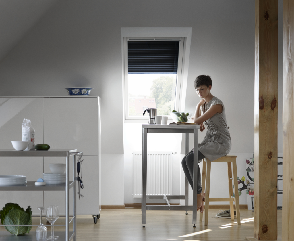 Artim Menuisier Cholet VELUX 108084 02 Xxl femme assise dans une cuisine devant une fenetre de toit VELUX