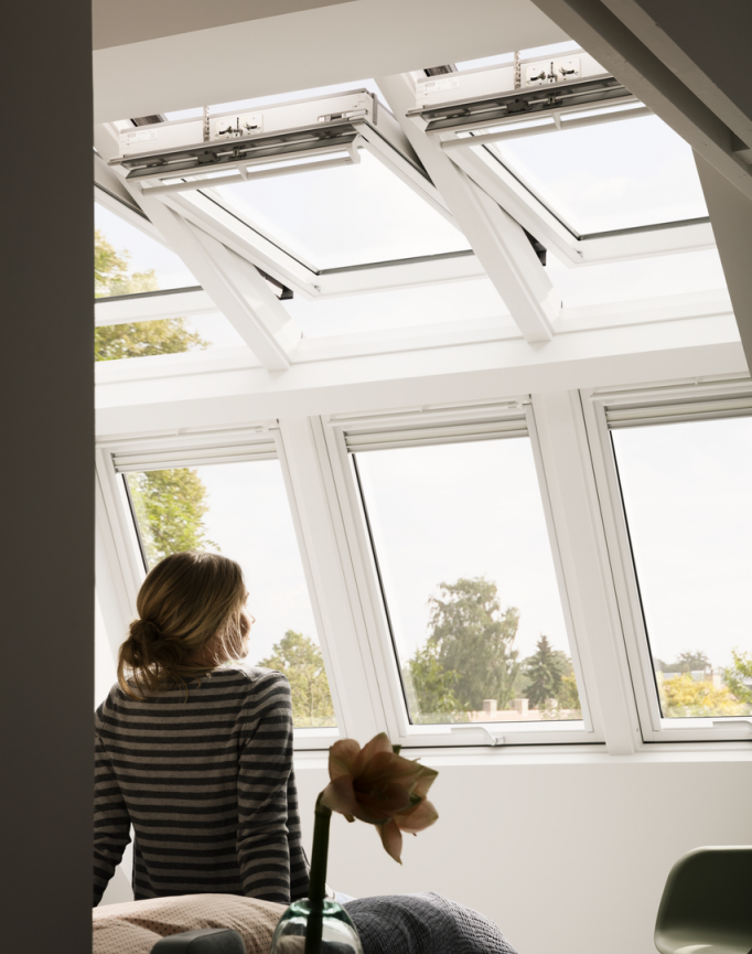 3 velux dans un séjour avec une femme vue de dos assise qui regarde à travers les velux