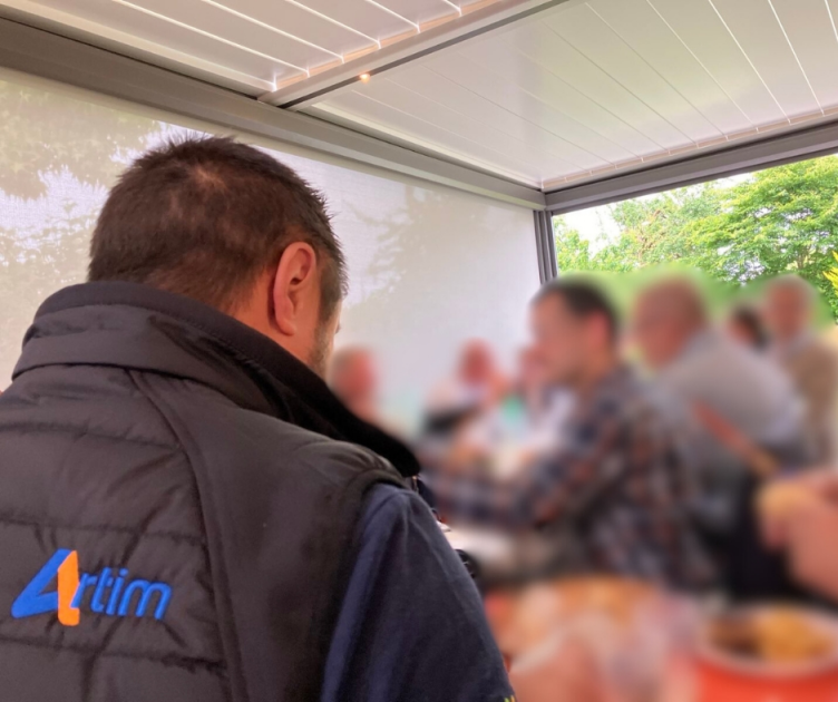 vue d'un groupe de personnes qui mangent sous une pergola détail d'un vêtement avec le logo ARTIM