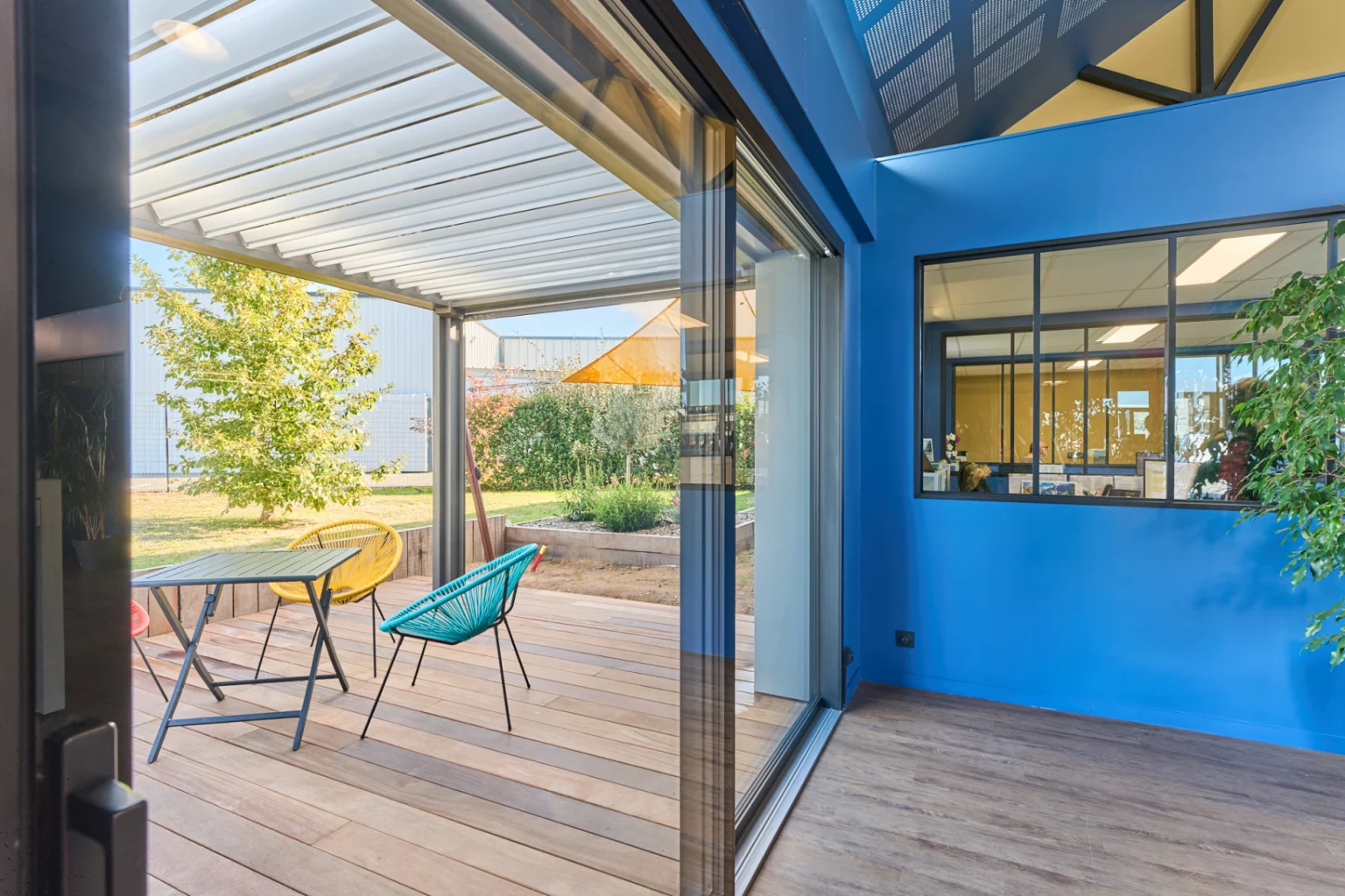 détail d'une baie "levant coulissant" de chez FINSTRAL noire dans notre studio de Cholet avec vue sur la terrasse bois et pergola bioclimatique