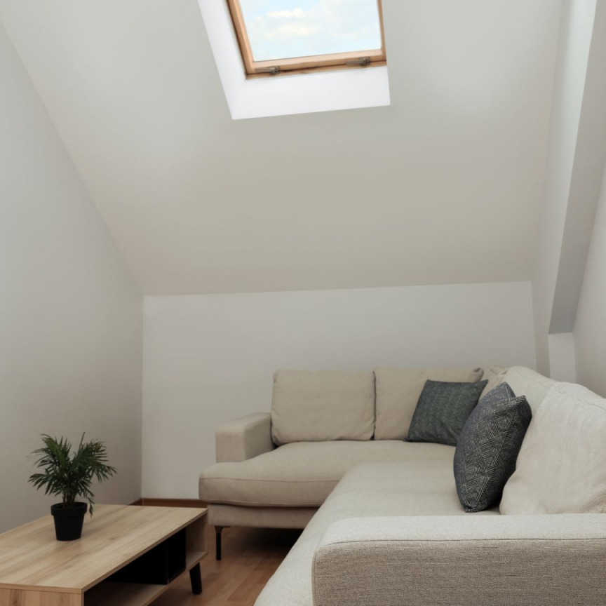 Artim Menuisier Cholet Amenagement Combles Cholet 31 salon aménagé sous les combles avec un canapé, une table basse et un VELUX à Cholet