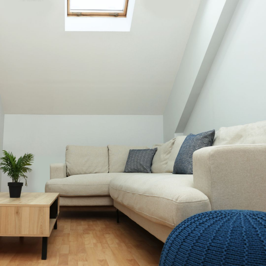 Artim Menuisier Cholet Amenagement Combles Cholet 32 salon aménagé sous les combles avec un canapé, une table basse et un VELUX à Beaupréau