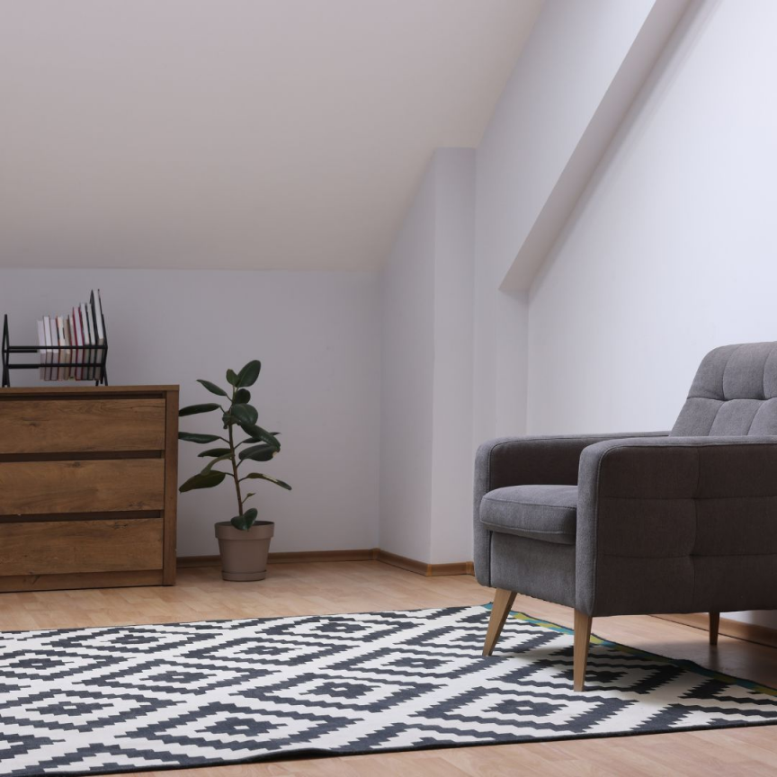 Artim Menuisier Cholet Amenagement Combles Cholet 33 salon aménagé sous les combles avec un fauteuil, une commode et un tapis