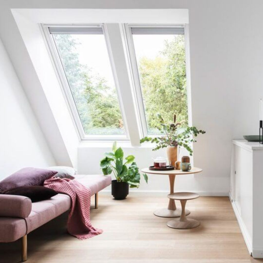 Artim Menuisier Cholet Amenagement Combles Cholet 36 petit coin salon aménagé sous les combles avec un fauteuil, une petite table avec de la deco et un velux jumo 2 en 1