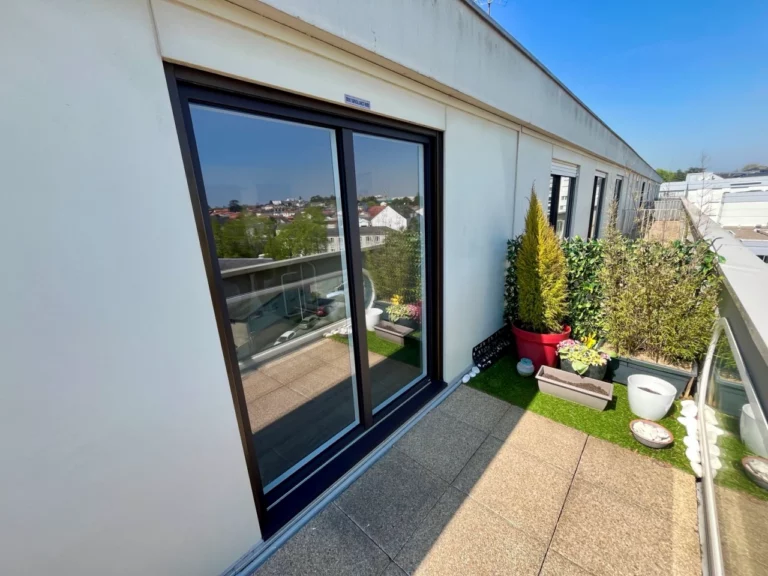 baie et fenêtre d'un immeuble de Cholet vue de l'extérieur avec terrasse sur le balcon avec verdure et pots