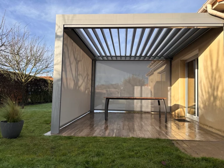 pergola bioclimatique avec 2 stores baissés sur une terrasse bois avec une table et un ouvert et lames ouvertes cholet