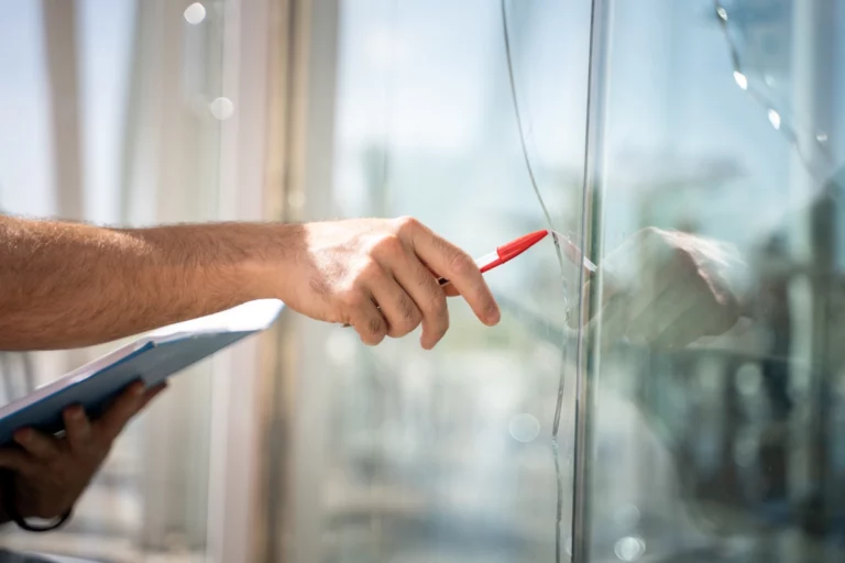 vitre de fenêtre cassée avec une main et un crayon pointée dessus