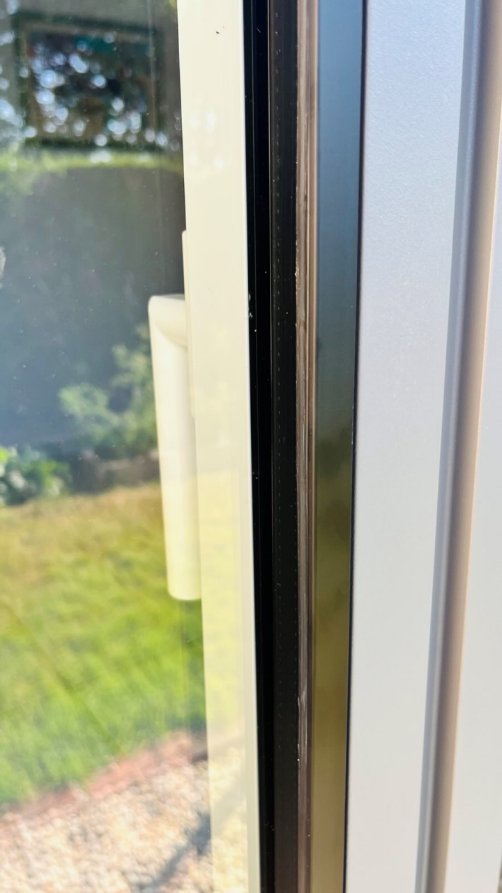 Fenêtre blanche à deux vantaux avec un ouvrant entrouvert et volet roulant partiellement baissé, dans une pièce lumineuse à Cholet.