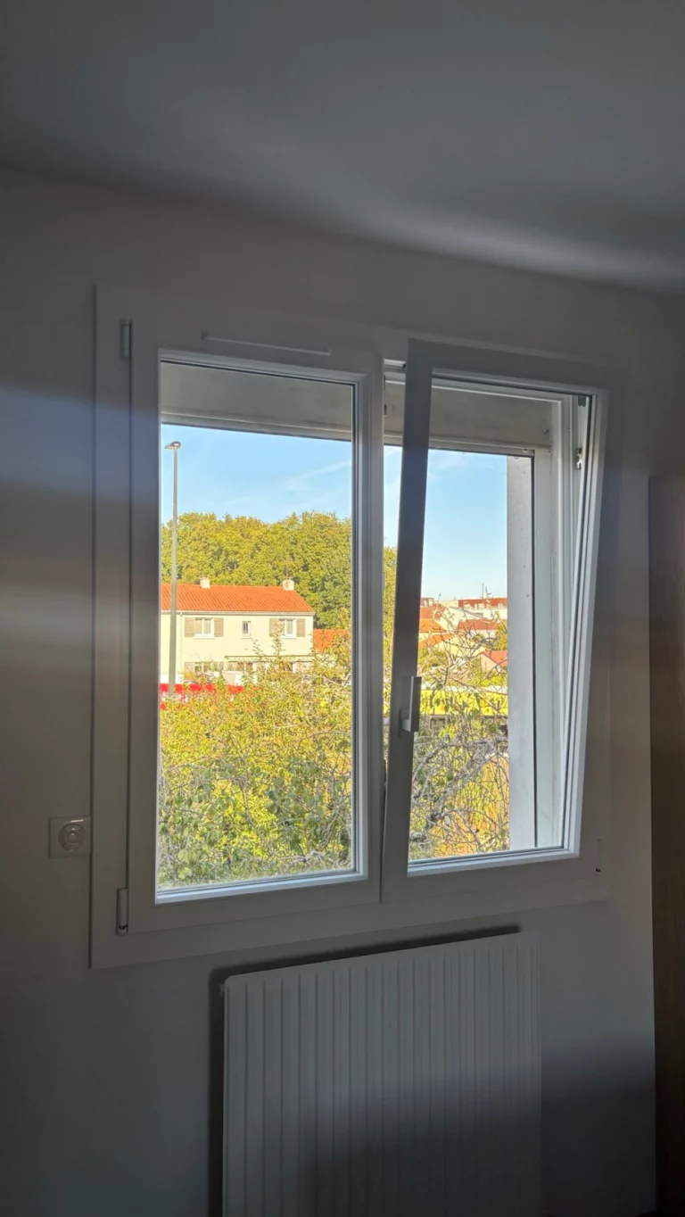 Gros plan sur le profil d’une menuiserie bicolore blanc et noir, avec poignée blanche et vue sur jardin à Cholet.