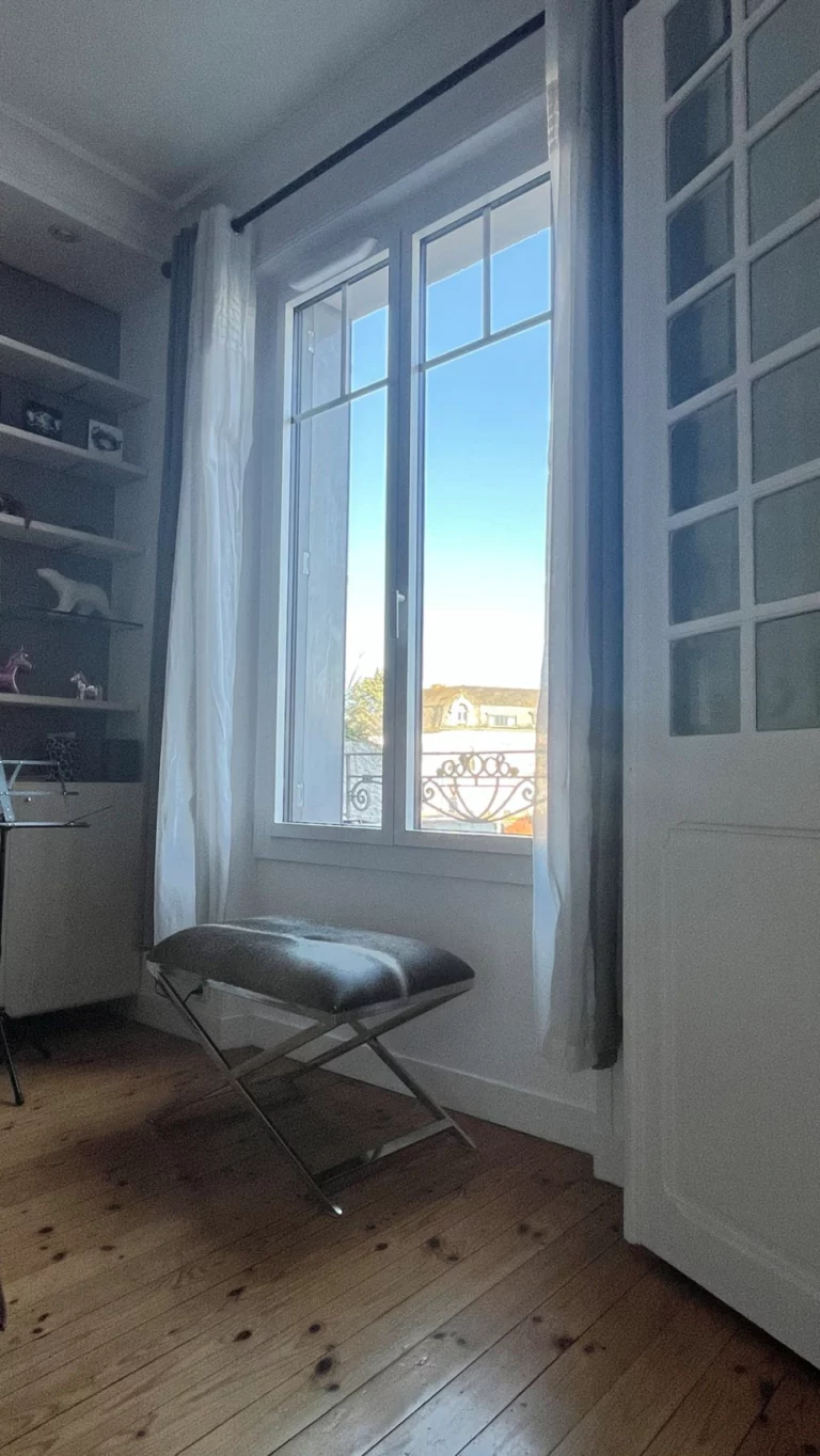 Grande fenêtre blanche avec rideaux légers dans un bureau ou salon, laissant entrer la lumière du jour à Cholet.