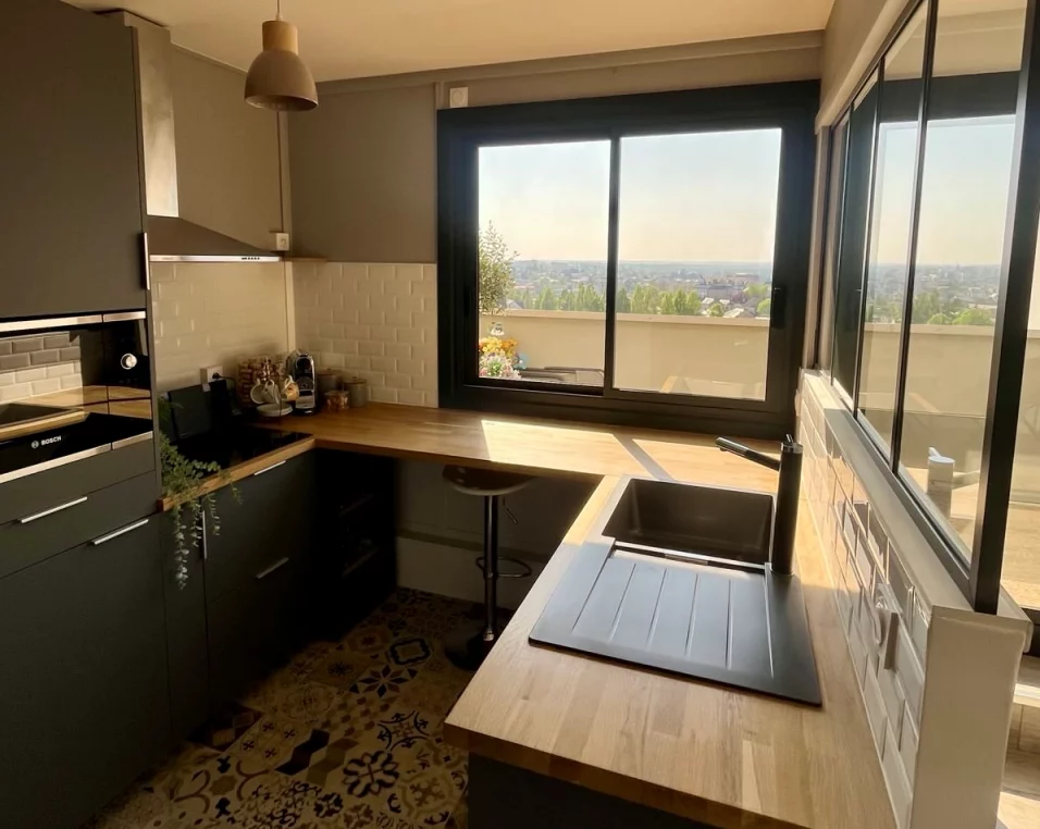 Artim Menuisier Cholet Fenetre Choletsignal 2025 04 10 175451 006 Fenêtre coulissante noire dans une cuisine moderne avec plan de travail bois et vue panoramique sur Cholet.