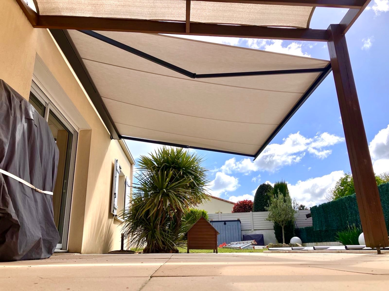 Artim Menuisier Cholet Store Banne3 Store banne toile claire sous pergola bois, solution d’ombre élégante et confortable.