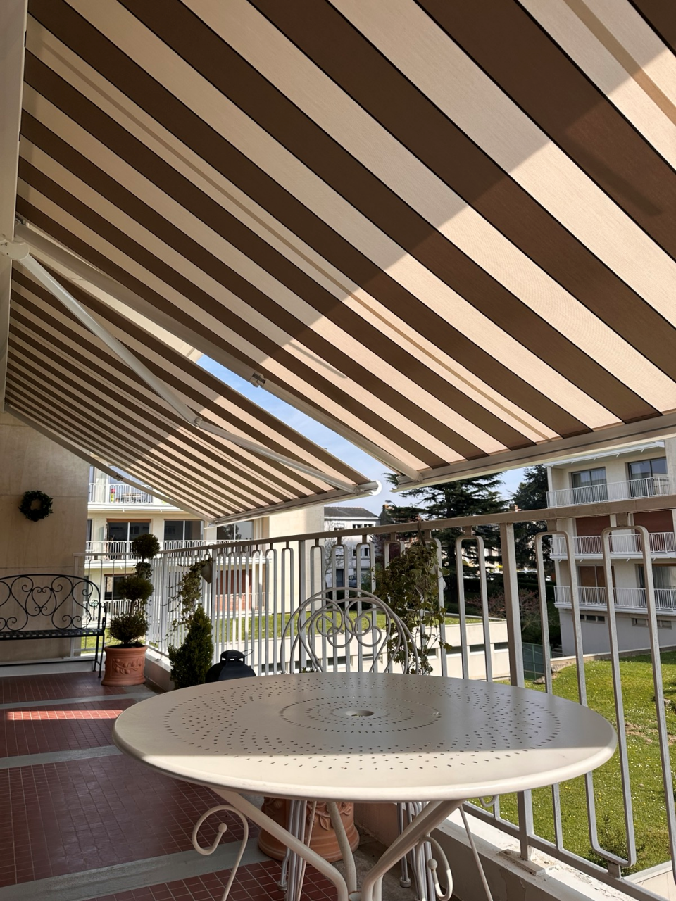 Artim Menuisier Cholet Store BanneIMG 4820 Store banne gris sur façade, grande avancée pour protéger la terrasse et limiter l’éblouissement.