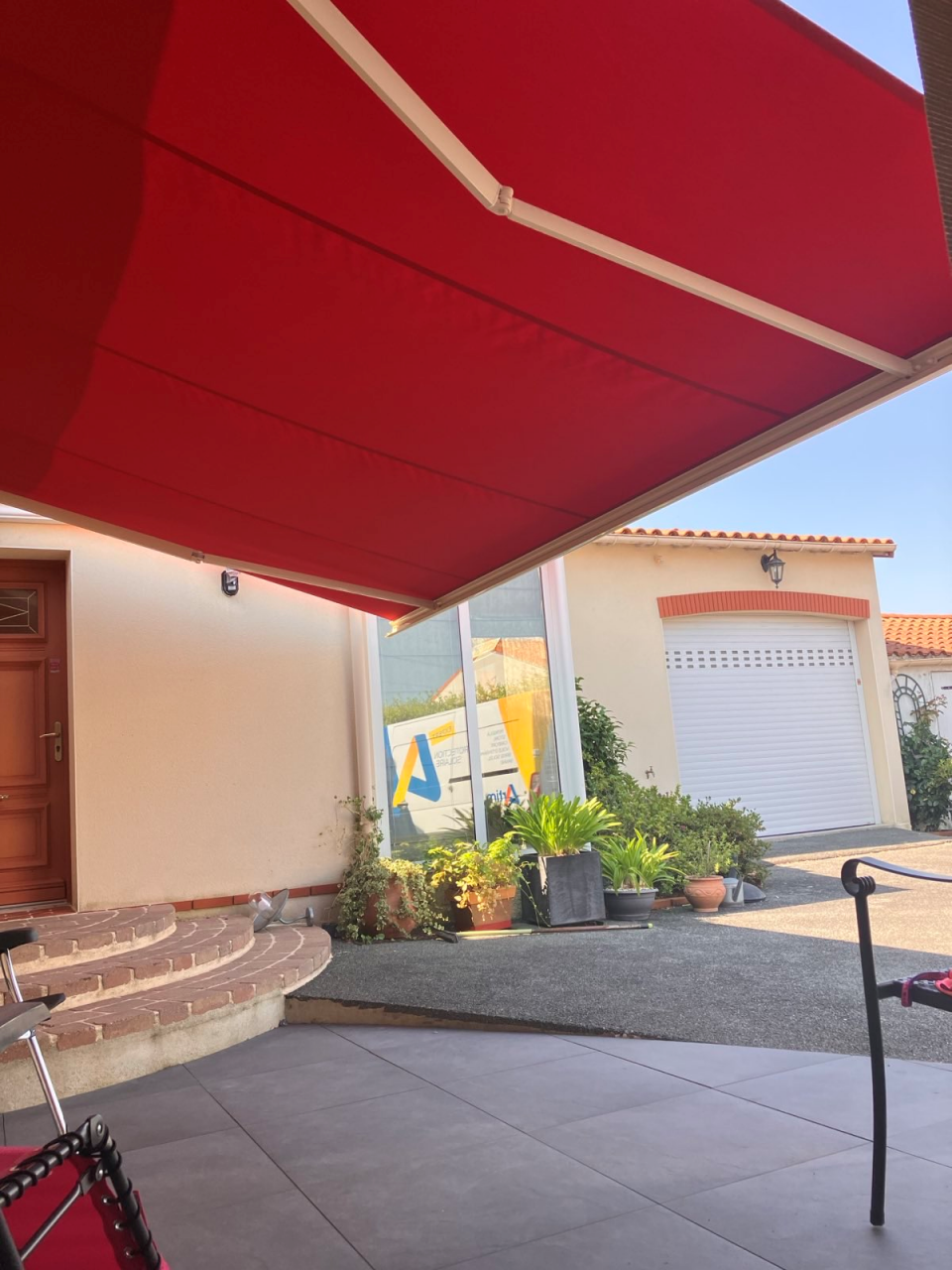 Artim Menuisier Cholet Store Bannesignal 2024 08 02 115124 003 Store banne rouge sur façade, grande zone d’ombre pour terrasse et entrée de maison.