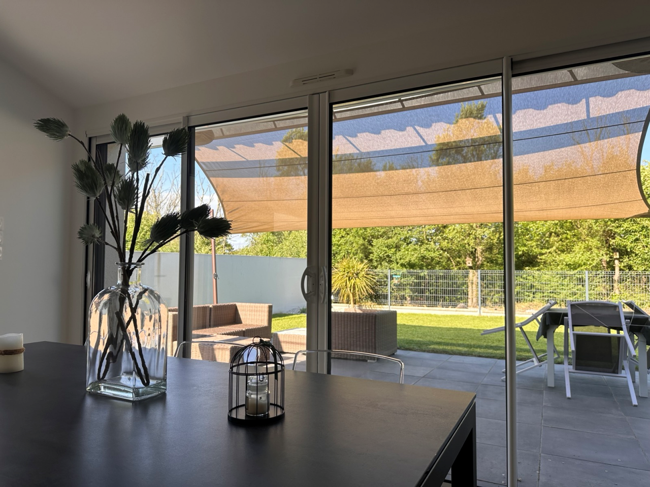 Artim Menuisier Cholet Voile Ombrage CholetIMG 4874 Voile d’ombrage vue depuis l’intérieur, ombrage de terrasse et jardin visible à travers baie vitrée – ARTIM vertou