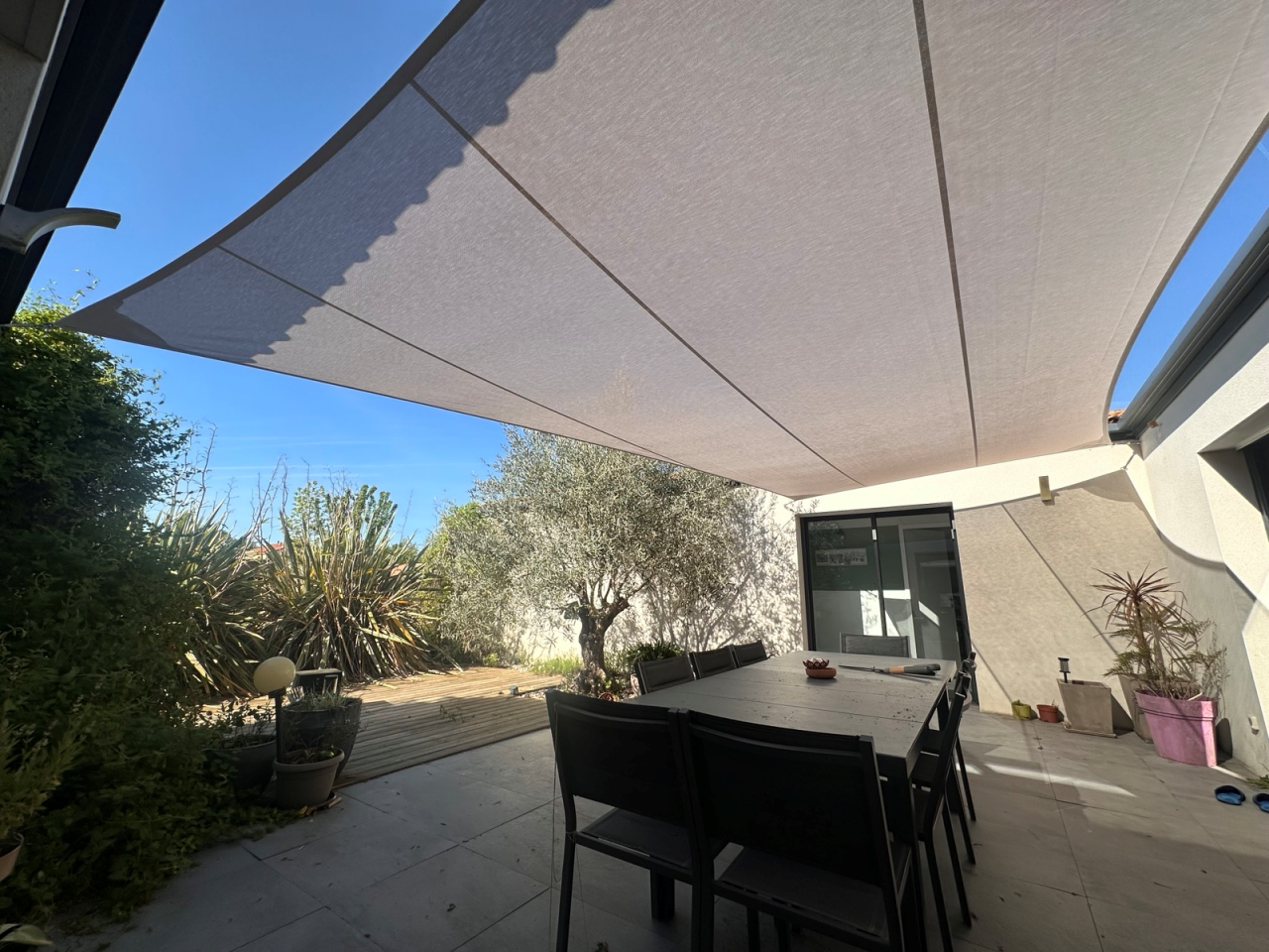 Artim Menuisier Cholet Voile Ombrage CholetIMG 4884 Vue sous voile d’ombrage beige sur mesure couvrant une table de terrasse, ombre douce et confortable – ARTIM beaupreau