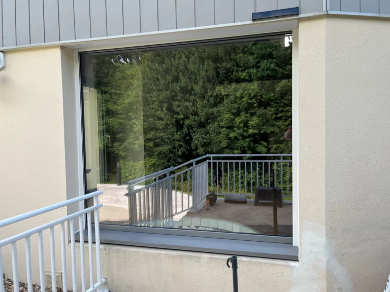Fenêtre isolante grand format avec menuiserie grise et vue sur jardin